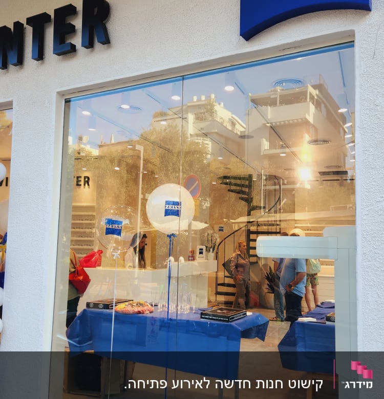 שולחן עם מפה כחולה, בלונים עם לוגו, כיבוד קל